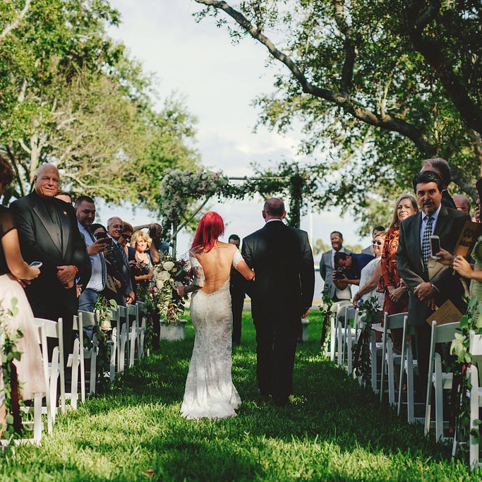bride walking down the aisle outdoors with red hair