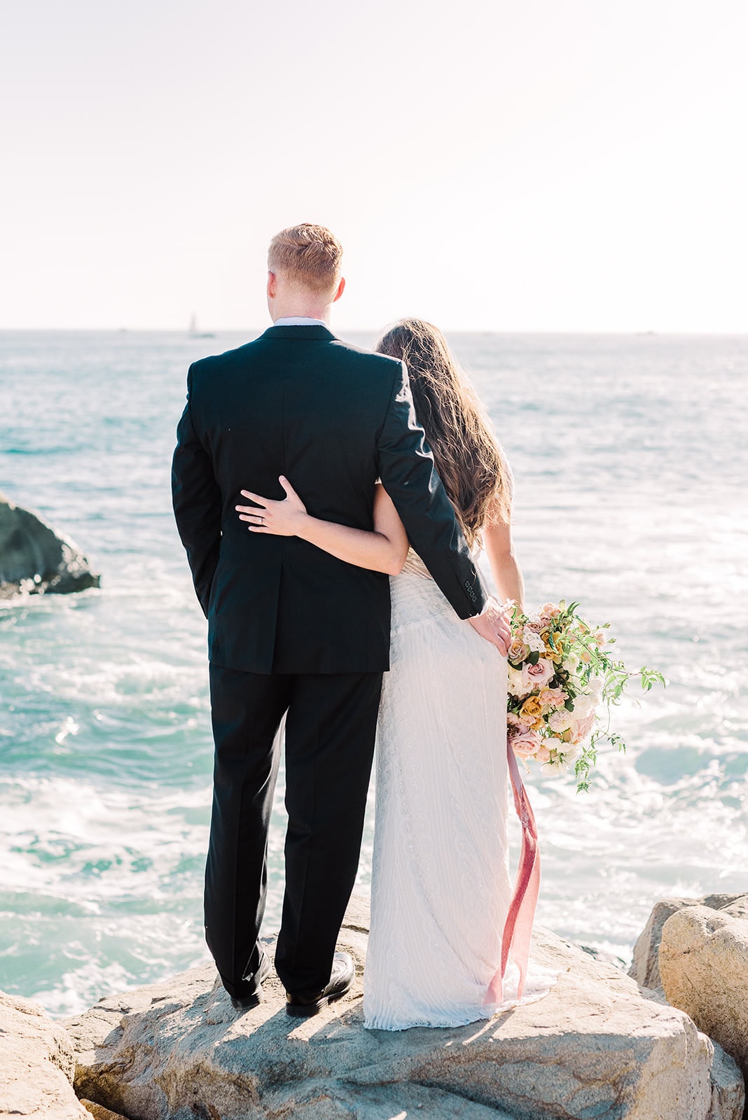 couple taking wedding photos by the ocean