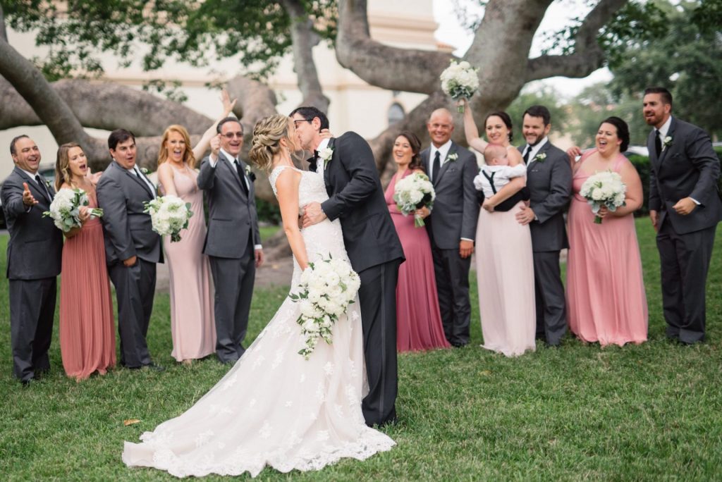 couple kissing in front of bridal party