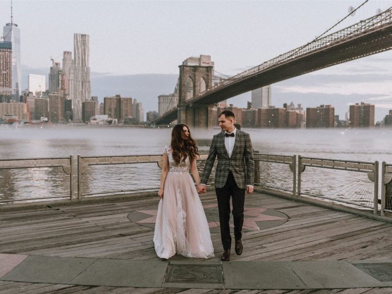 married couple taking photos by bridge in new york