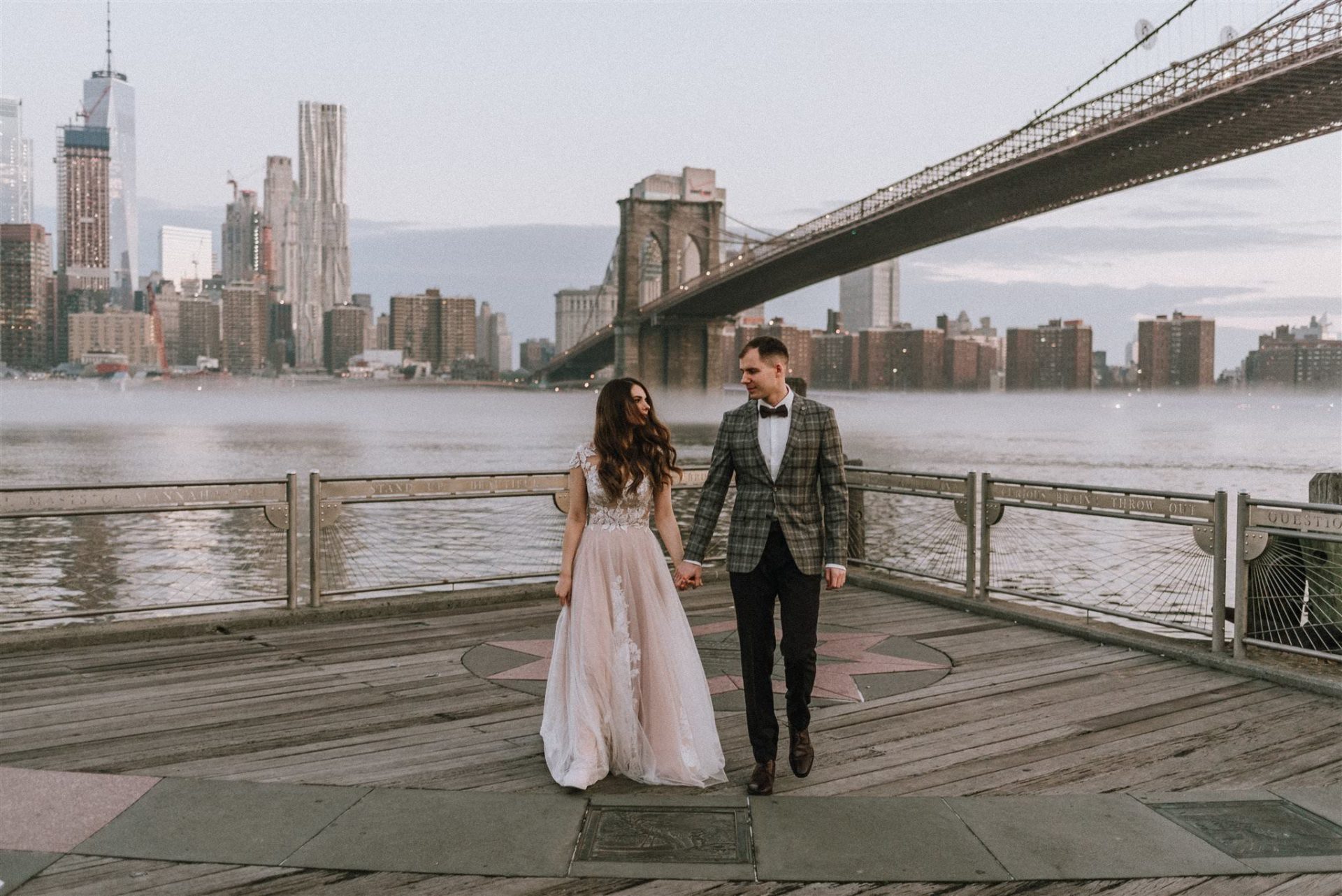 married couple taking photos by bridge in new york