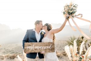 couple holding just married sign and kissing