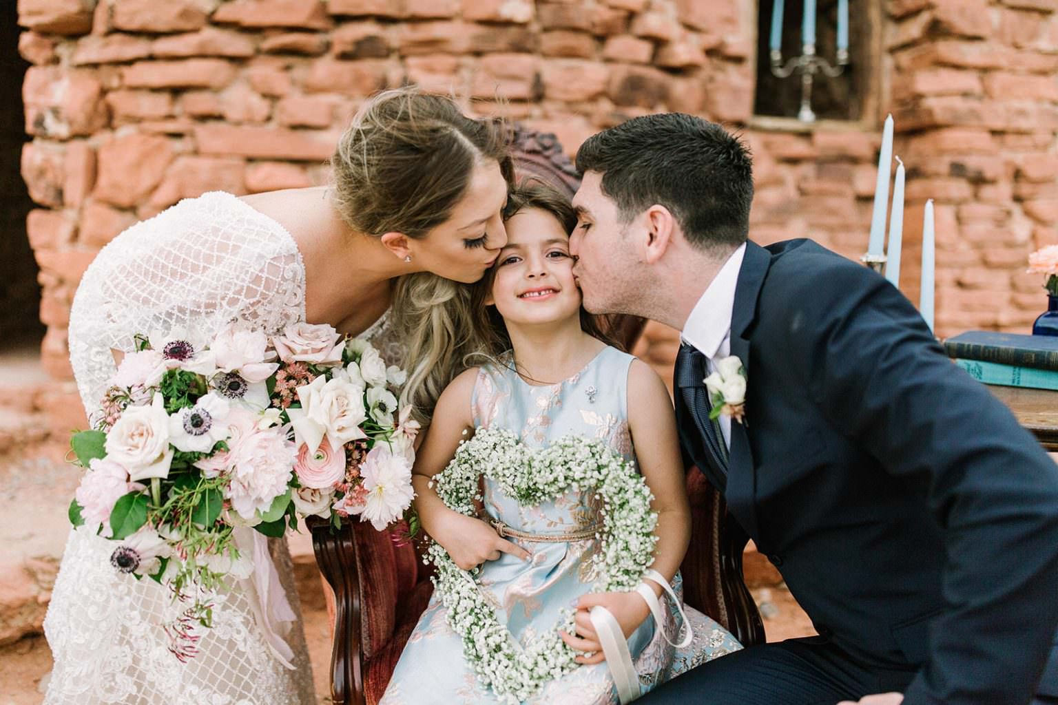 married couple kissing their kid after wedding
