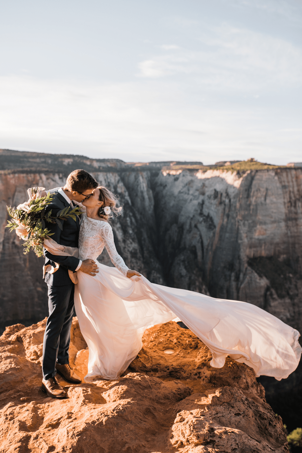 Couple kissing during their wedding on a cliff